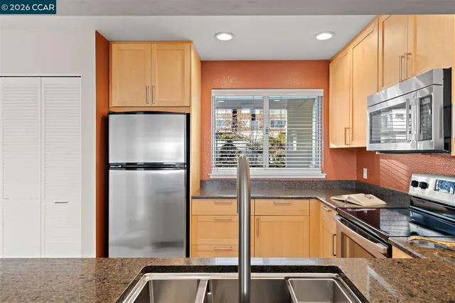 a kitchen with stainless steel appliances granite countertop a refrigerator a sink and a stove