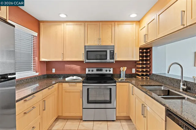 a kitchen with granite countertop a stove top oven sink and cabinets