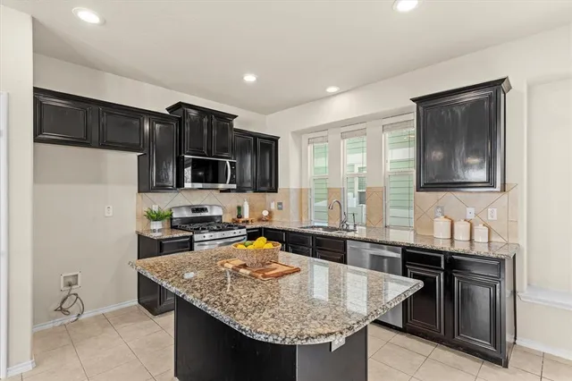 a kitchen with stainless steel appliances granite countertop a sink refrigerator and microwave