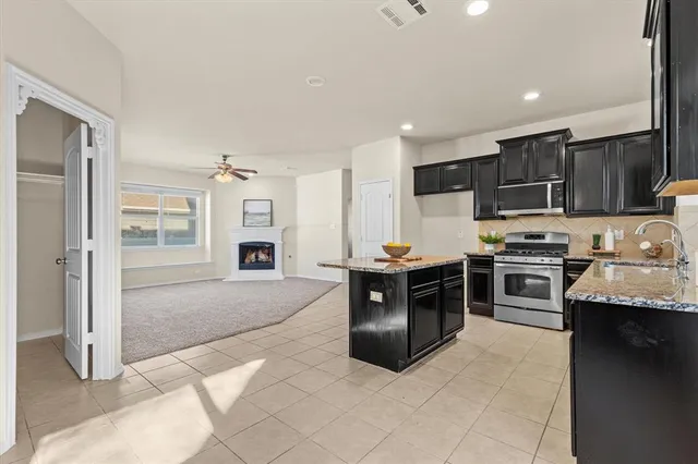 a kitchen with stainless steel appliances granite countertop a stove top oven a sink and dishwasher