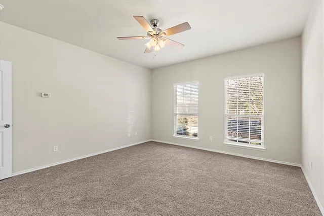 an empty room with chandelier fan and windows