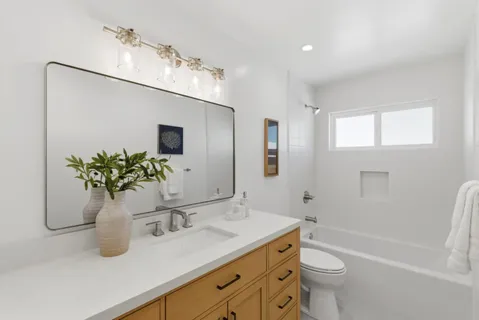 a bathroom with a granite countertop sink a toilet and mirror