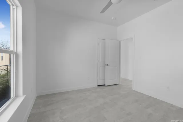 an empty room with windows and fan