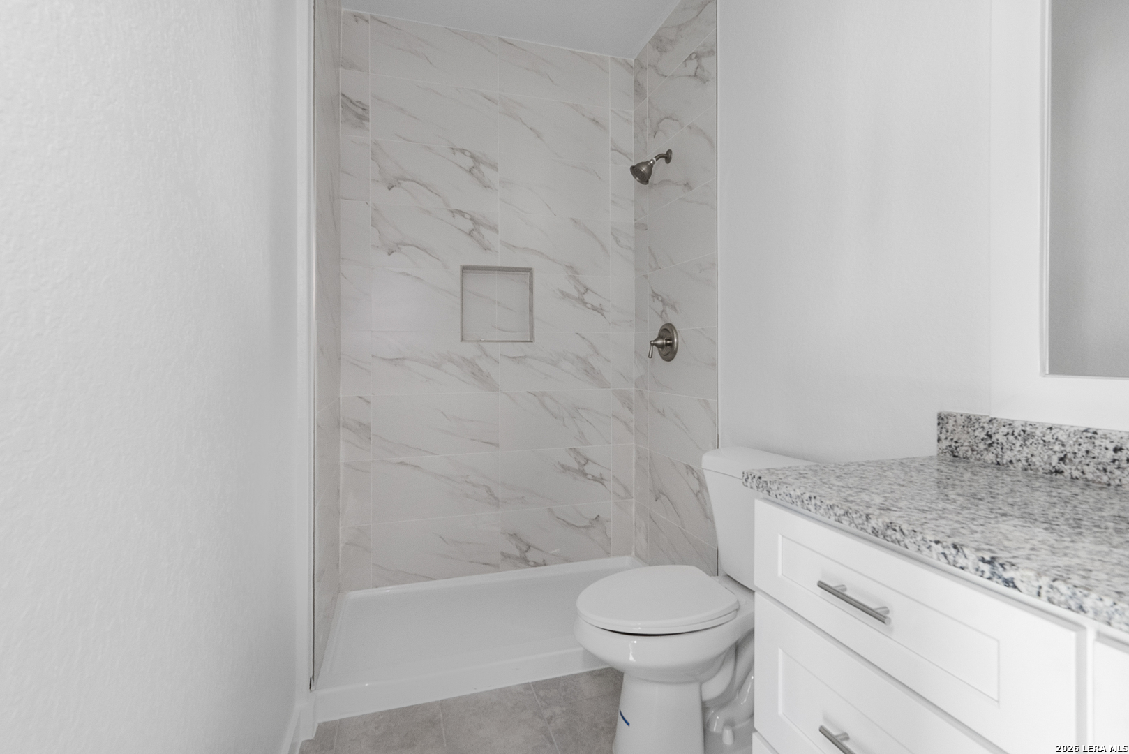 804 Peach Street Jourdanton, TX 78026 - Photo 15 of 16 a bathroom with a granite countertop toilet a sink and bathtub