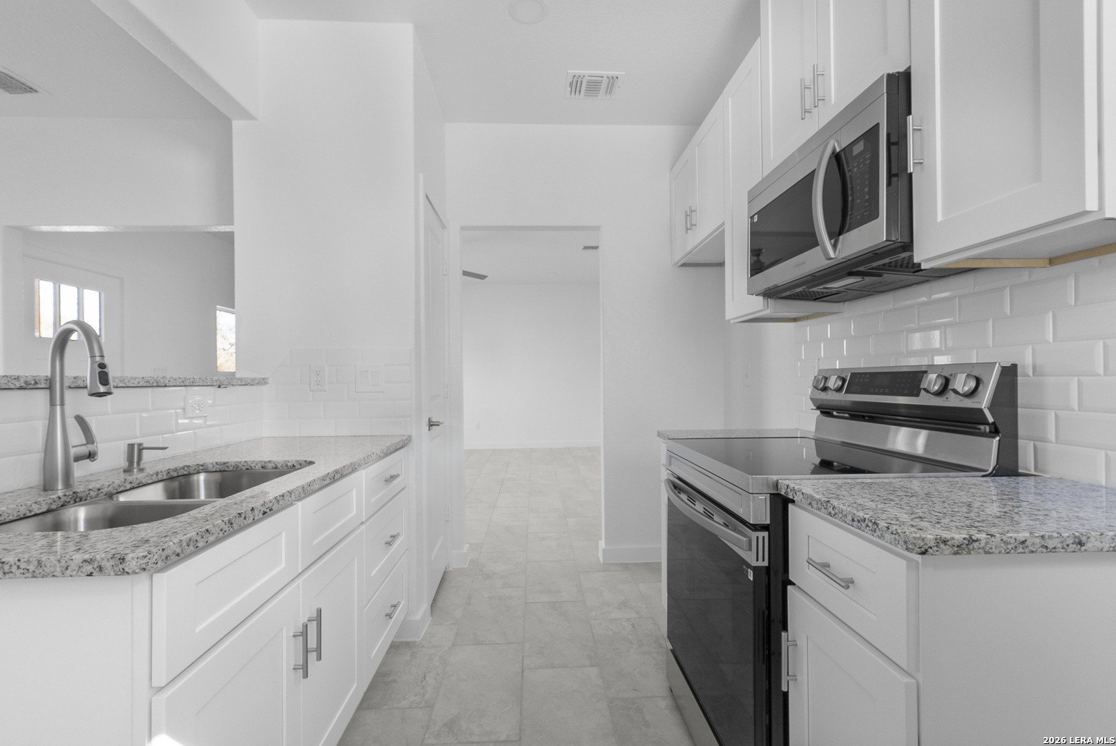 804 Peach Street Jourdanton, TX 78026 - Photo 7 of 16 a kitchen with stainless steel appliances granite countertop a sink stove and microwave