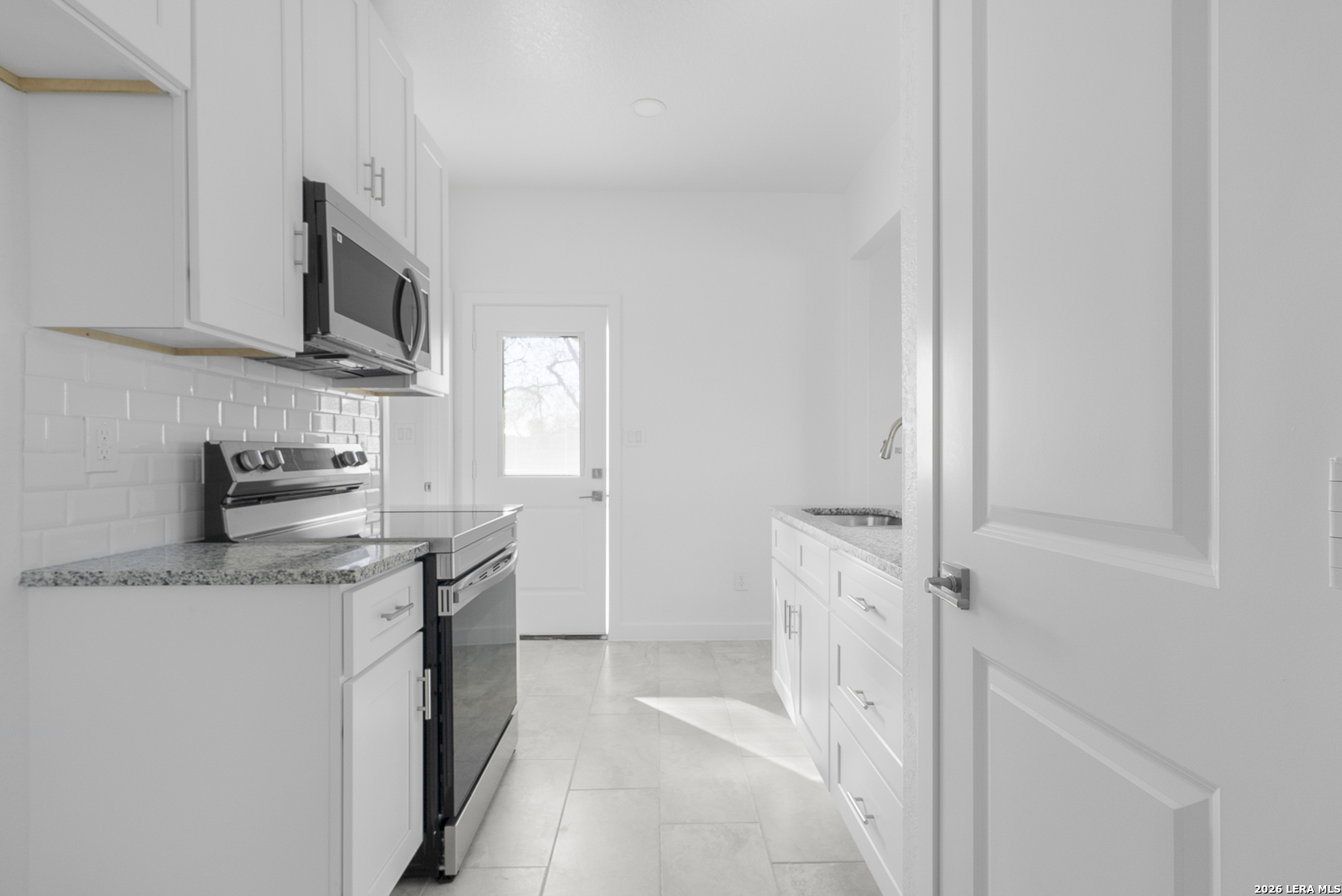804 Peach Street Jourdanton, TX 78026 - Photo 8 of 16 a kitchen with stainless steel appliances granite countertop a sink and a stove top oven
