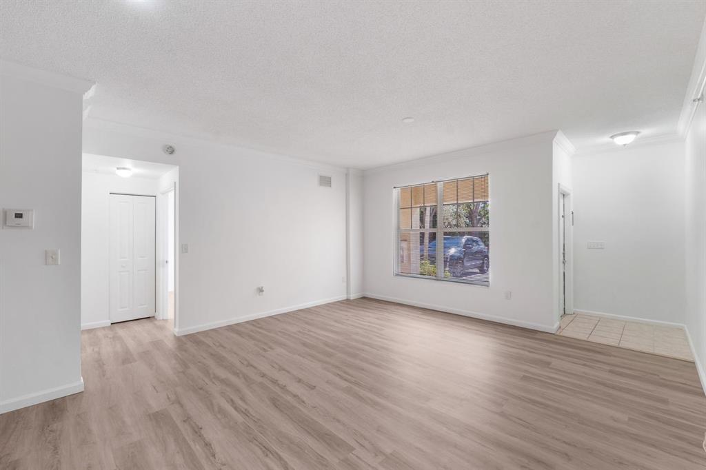 5800 West Sample Road, Unit 102 Coral Springs, FL 33067 - Photo 11 of 23 a view of an empty room with wooden floor and a window