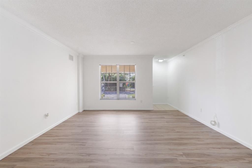 5800 West Sample Road, Unit 102 Coral Springs, FL 33067 - Photo 12 of 23 a view of an empty room with wooden floor and a window