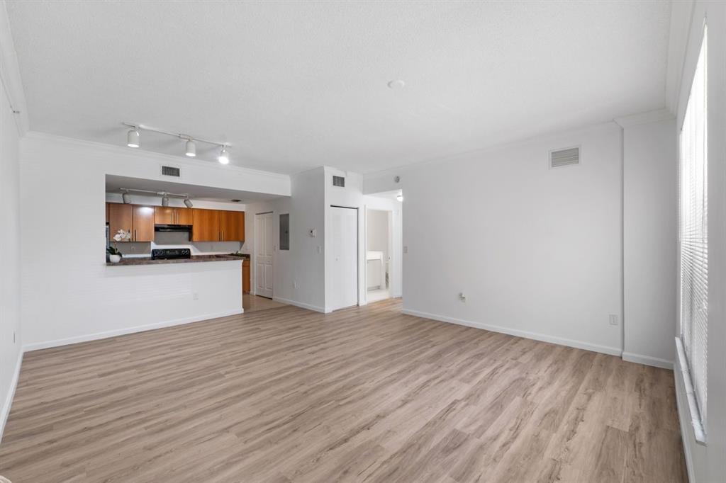 5800 West Sample Road, Unit 102 Coral Springs, FL 33067 - Photo 5 of 23 a view of an empty room with wooden floor and a kitchen