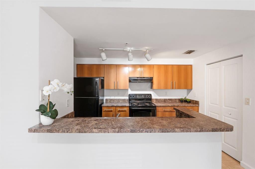 5800 West Sample Road, Unit 102 Coral Springs, FL 33067 - Photo 6 of 23 a kitchen with stainless steel appliances granite countertop a sink and a white cabinets