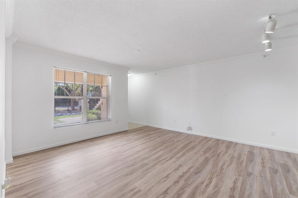 5800 West Sample Road, Unit 102 Coral Springs, FL 33067 - Photo 10 of 23 an empty room with wooden floor and windows