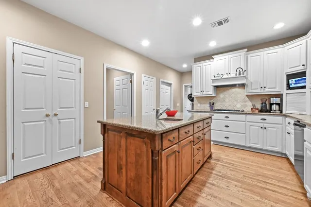 a kitchen with stainless steel appliances granite countertop a table chairs sink and cabinets