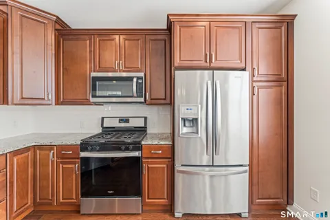 a kitchen with granite countertop wooden cabinets and stainless steel appliances