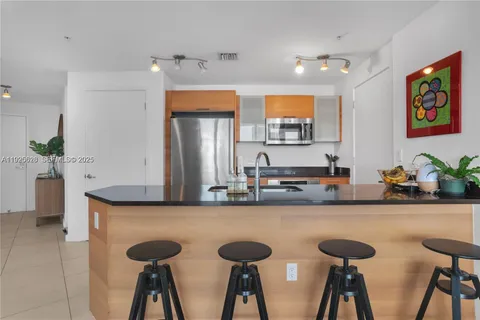 a kitchen with stainless steel appliances granite countertop a sink a stove and a dining table with wooden floor