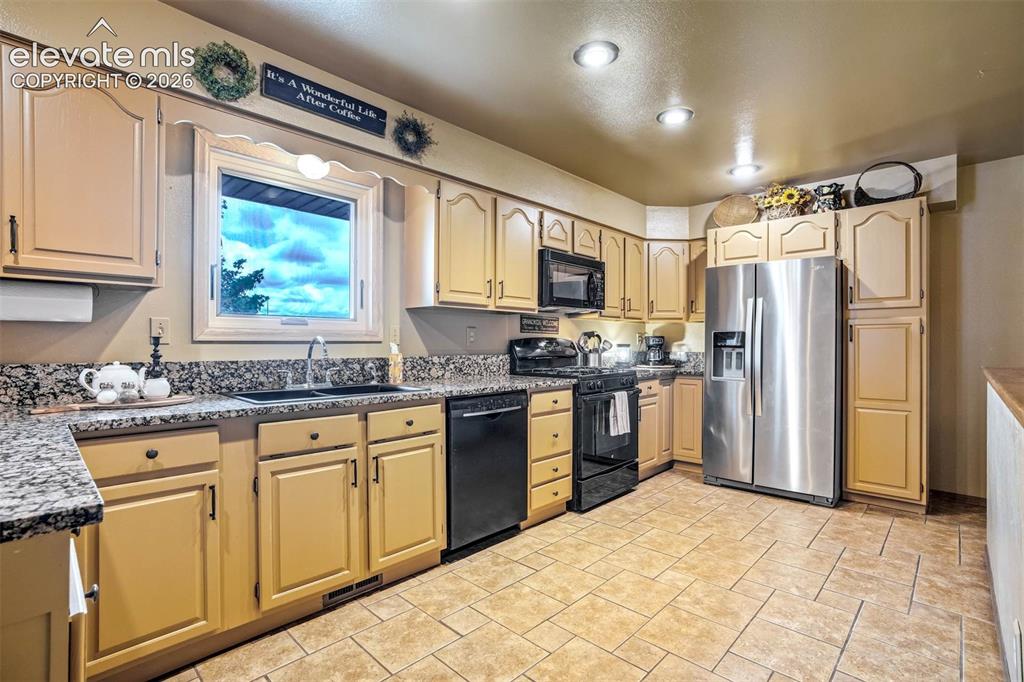7585 Ponca Road Colorado Springs, CO 80908 - Photo 11 of 49 A chef's delight- ample cabinetry, pullout to right of frig for food/spice storage, gas range/oven, granite counters, overhead lighting, window to east-meadow views