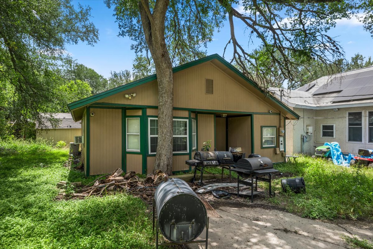 151 High Ridge Drive Del Valle, TX 78617 - Photo 7 of 8 Rear facade with outdoor grilling space amidst mature trees, creating a shaded setting.