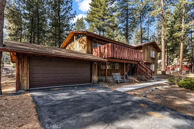 a view of a house with large trees and wooden fence