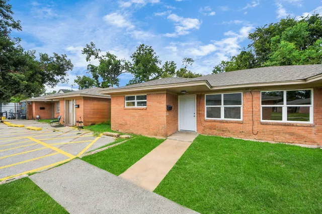 a view of a yard in front of a house with a large tree