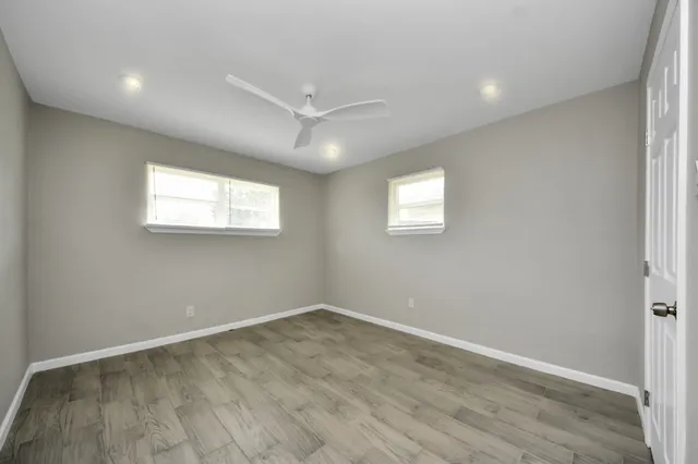 an empty room with wooden floor and windows