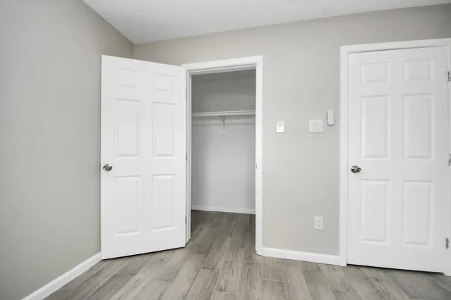 an empty room with wooden floor and closet area