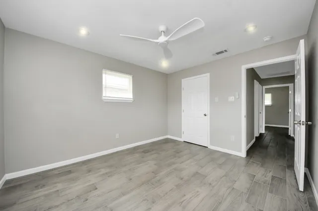 an empty room with wooden floor and windows