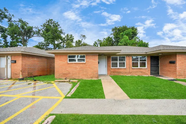 a view of a yard in front of a house with large windows