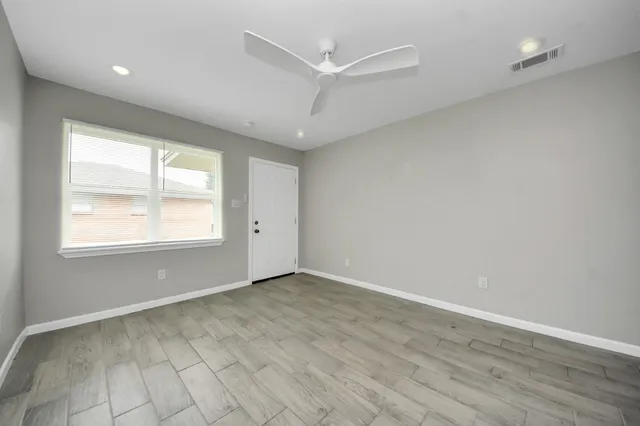 an empty room with wooden floor and windows