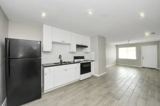 a kitchen with granite countertop a refrigerator stove top oven and sink