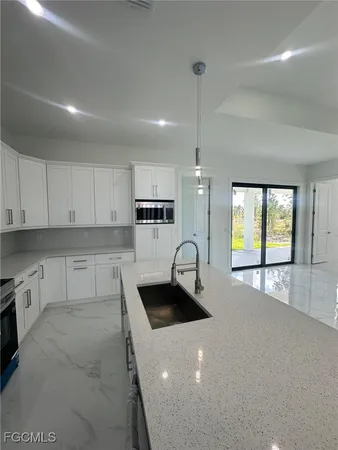 a kitchen with stainless steel appliances a sink a stove and white cabinets