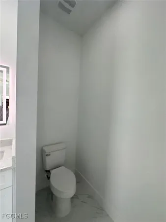 a white toilet sitting next to a white wall