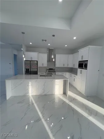 a large white kitchen with kitchen island a sink a stove a microwave and white cabinets