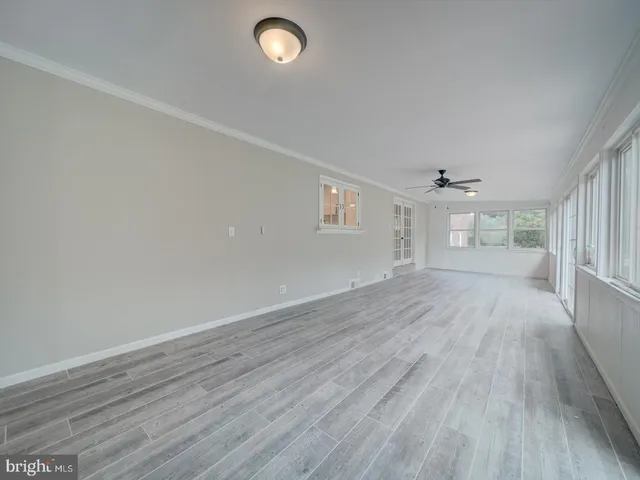a view of an empty room with wooden floor and closet