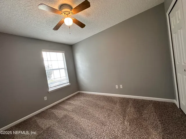 an empty room with windows and fan