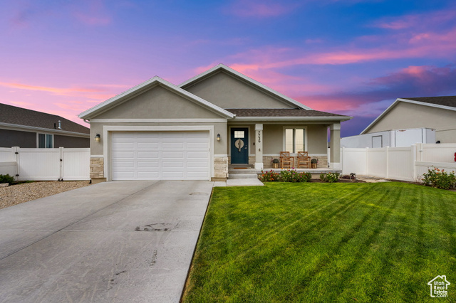 Ranch-style house featuring a porch, stucco siding, a garage, stone siding, and driveway