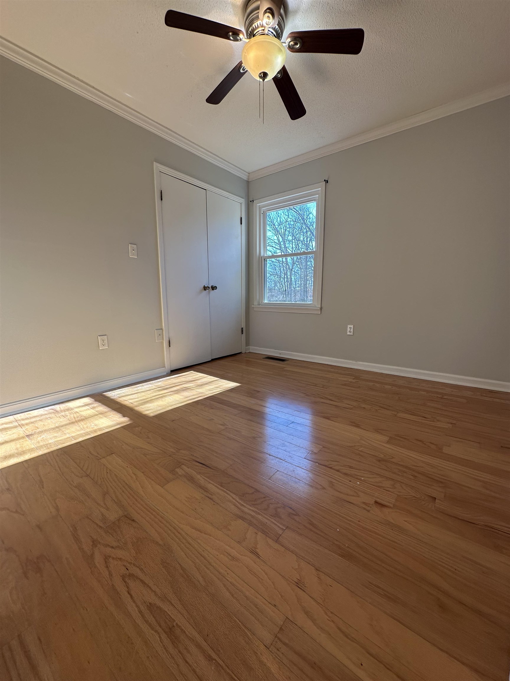 141 Pecan Street Selmer, TN 38375 - Photo 26 of 35 an empty room with wooden floor chandelier fan and windows
