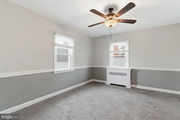 an empty room with windows and ceiling fan
