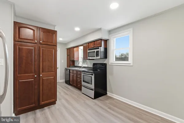 a kitchen with stainless steel appliances granite countertop a refrigerator microwave and wooden floor