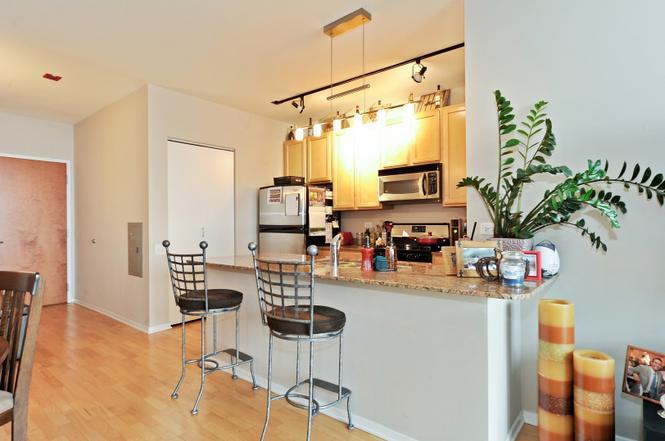 210 South Desplaines Street, Unit 2104 Chicago, IL 60661 - Photo 5 of 9 a kitchen with stainless steel appliances a stove a refrigerator and a dining table