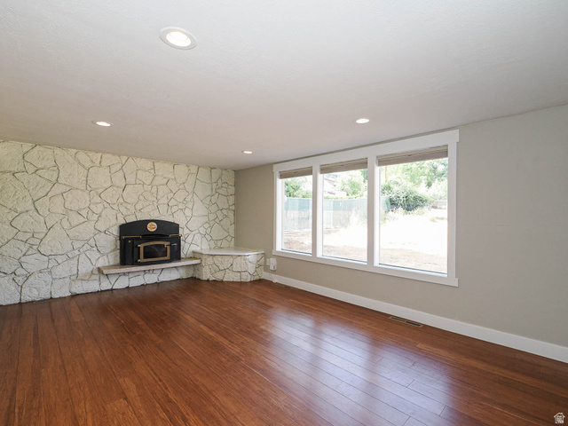 154 East 3000th Street South Bountiful, UT 84010 - Photo 7 of 37 Spacious living area featuring rich wood-finish flooring, a stone-clad accent wall with a built-in fireplace, and recessed ceiling lighting