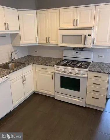 a kitchen with granite countertop white cabinets and white appliances