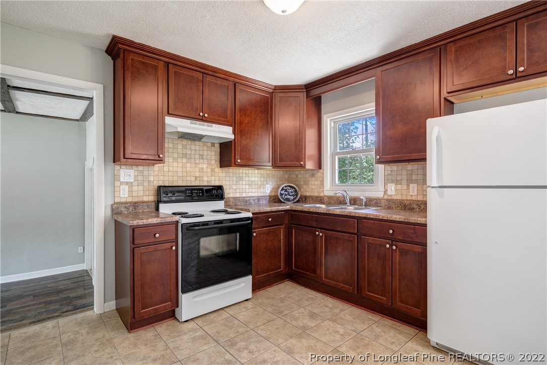 4549 Ruby Road Fayetteville, NC 28311 - Photo 8 of 20 a kitchen with stainless steel appliances granite countertop wood cabinets a stove top oven a sink and dishwasher