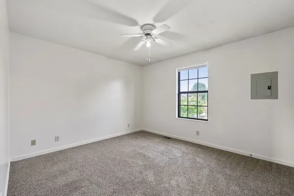 an empty room with a ceiling fan and window