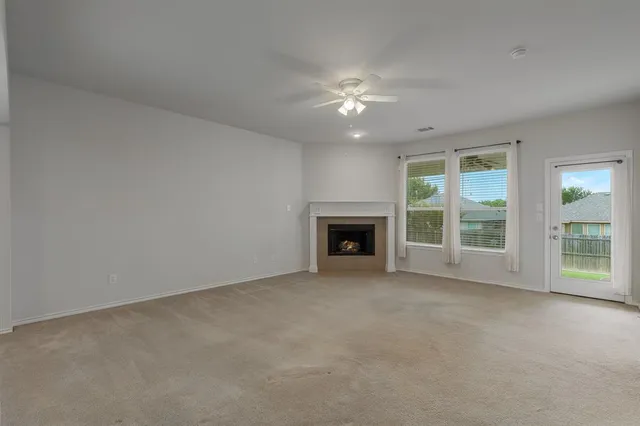 an empty room with windows fireplace and fans