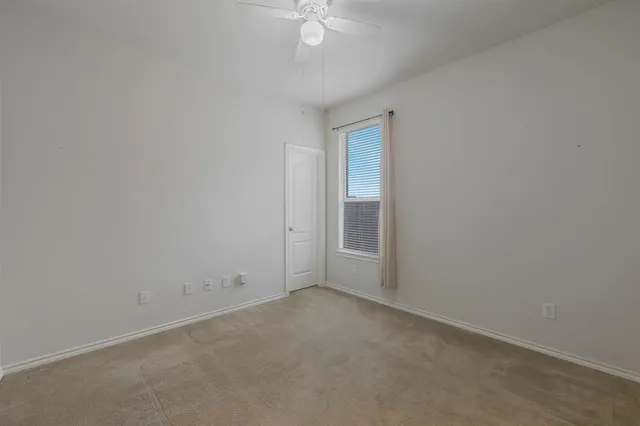 an empty room with a ceiling fan and a window