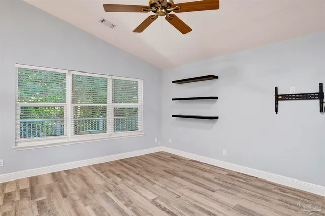 a view of empty room with wooden floor and fan