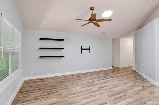 a view of empty room with wooden floor and fan