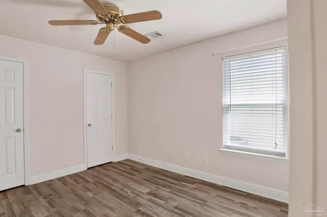 a view of empty room with wooden floor and fan