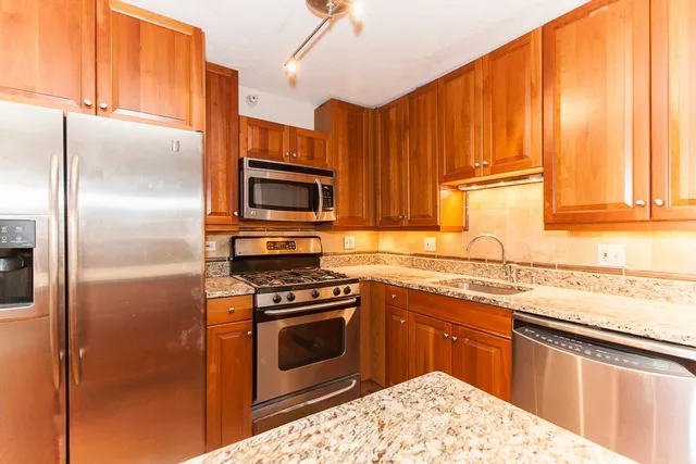 a kitchen with stainless steel appliances granite countertop a stove a refrigerator and a sink