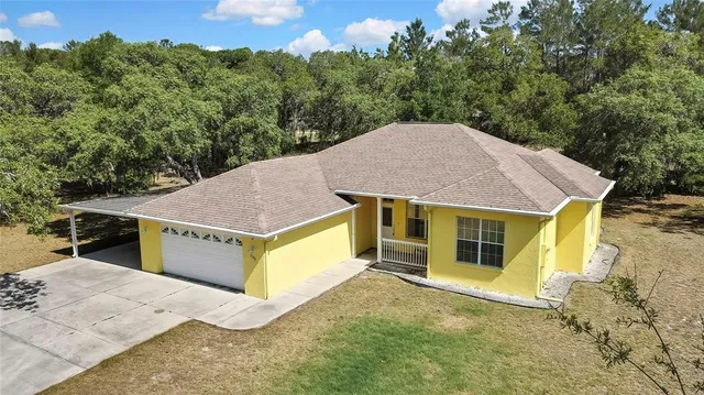 a aerial view of a house with a yard and large tree