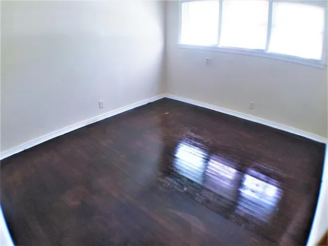 an empty room with wooden floor and windows in it